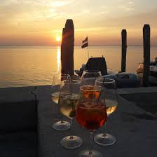 Tramonto sulla Laguna di Venezia con calici di vino sul tavolo davanti all'acqua